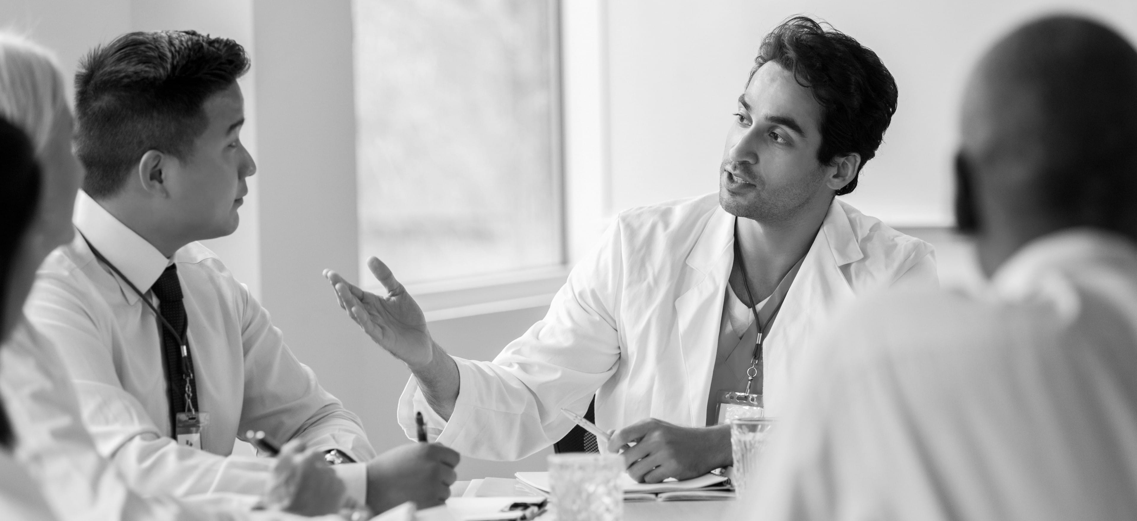 Doctors sitting at a table talking amongst each other.